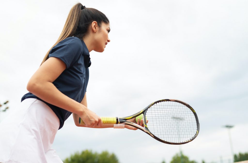 Young happy woman playing tennis at tennis court